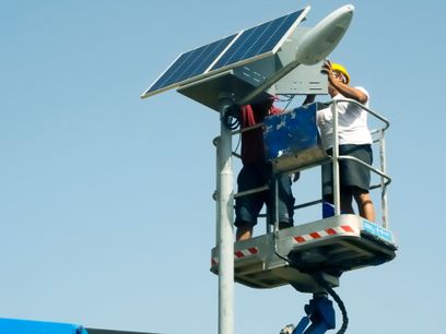 Los trabajadores que realizan la instalación de un kit fotovoltaico para la lámpara de calle